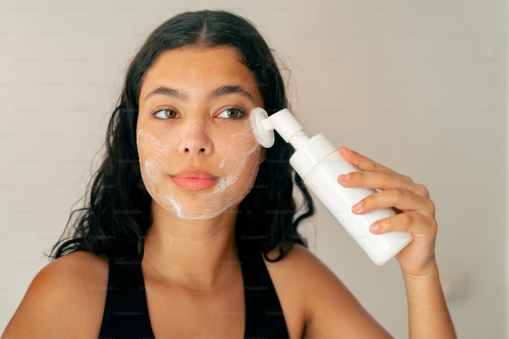 a woman with a facial mask on holding a bottle of lotion