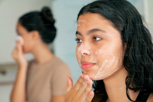 a woman is shaving her face in front of a mirror