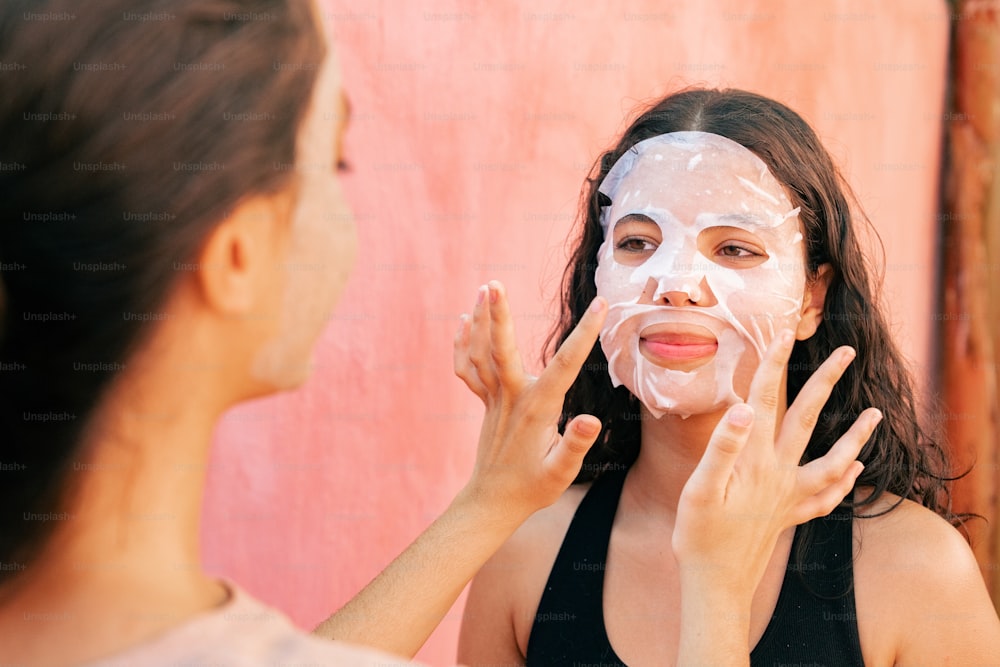 a woman is putting a mask on her face