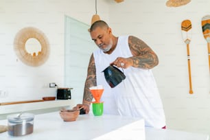 a man pouring something into a bowl on top of a counter