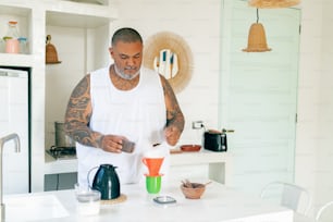 a man standing in a kitchen preparing a drink