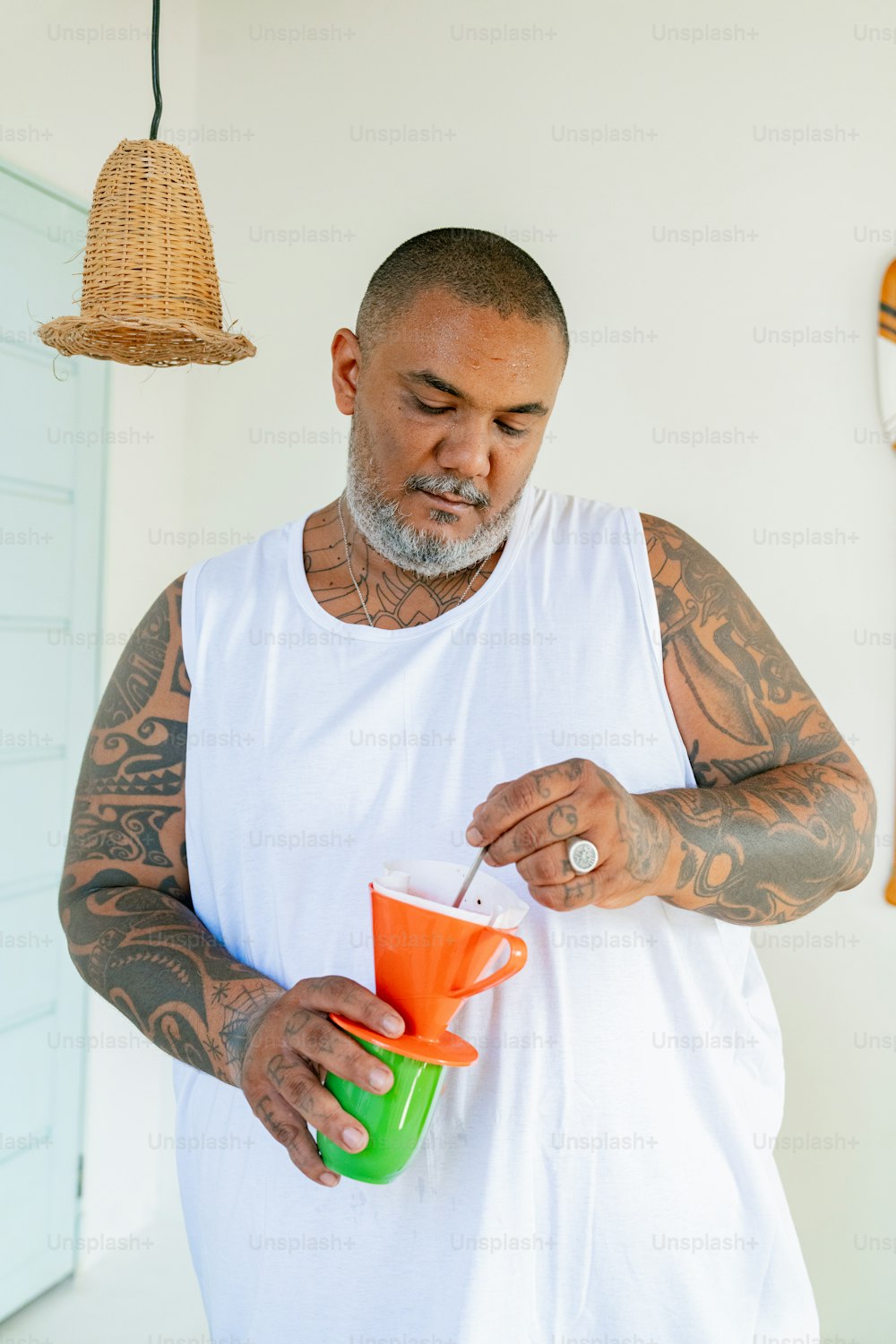un uomo con tatuaggi che tiene una tazza in mano