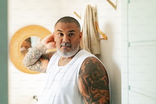 a man with tattoos standing in front of a mirror