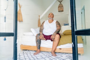 a man with tattoos sitting on a bed