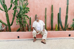 a man sitting on a bench in front of a cactus