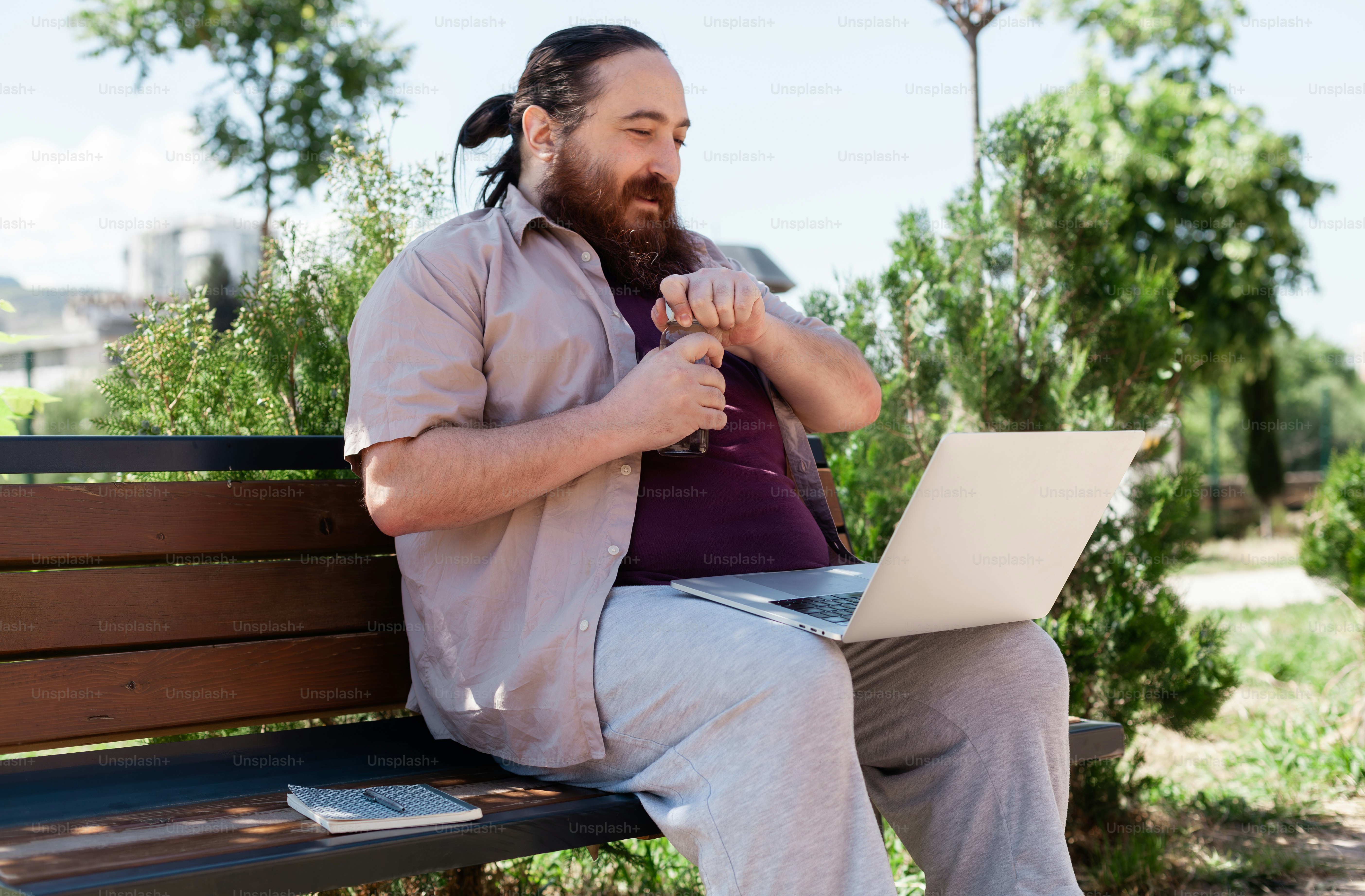 a man sitting on a bench using a laptop computer