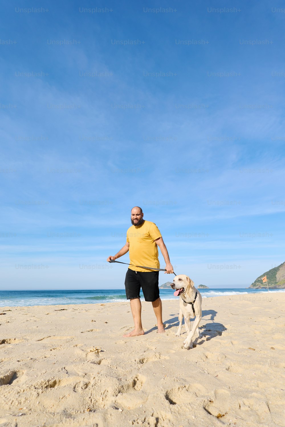a man standing on a beach with a dog