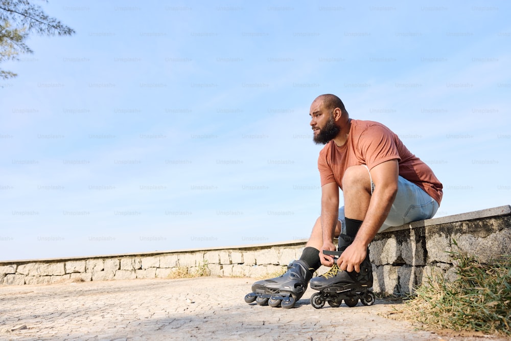 a man sitting on a stone wall with a skateboard