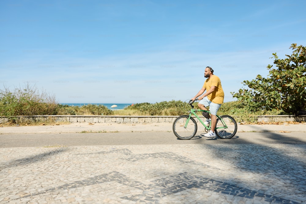 a man riding a bike down a street next to the ocean
