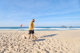 a man walking a dog on the beach