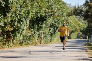 a man in a yellow shirt running down a road