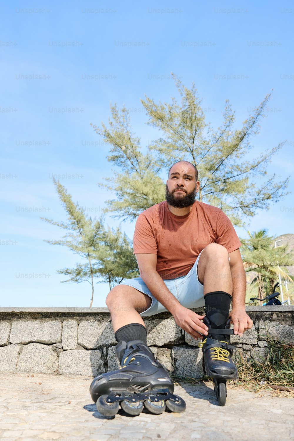 a man sitting on a stone wall next to a pair of roller skates