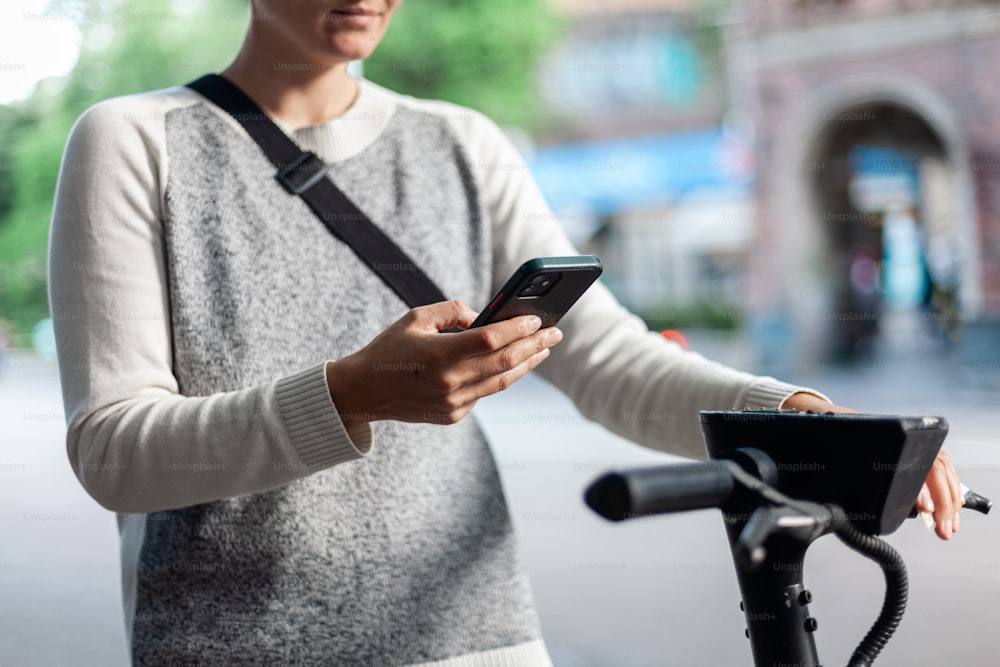 a woman using a cell phone while standing next to a bike