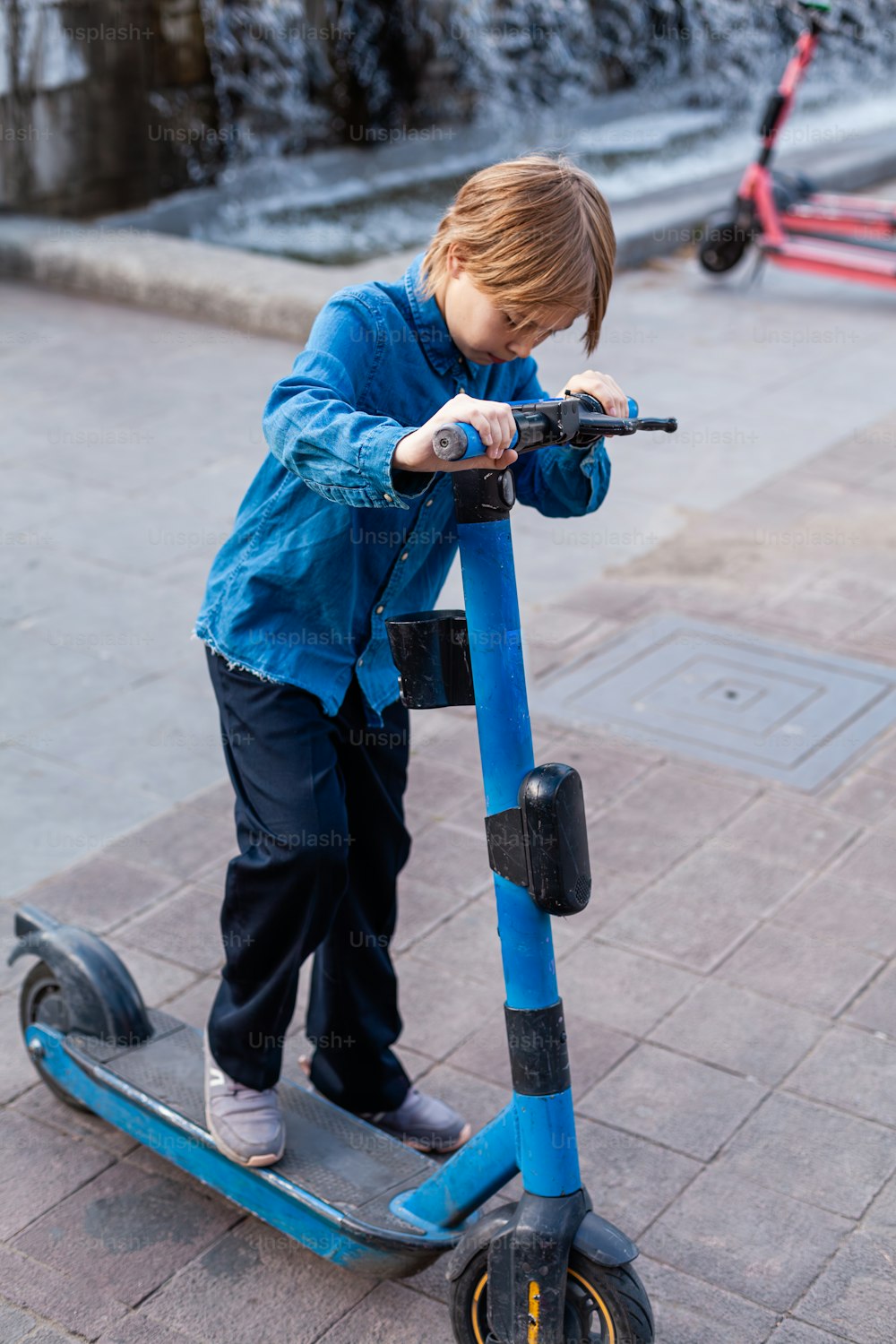 a young boy riding a scooter on a sidewalk