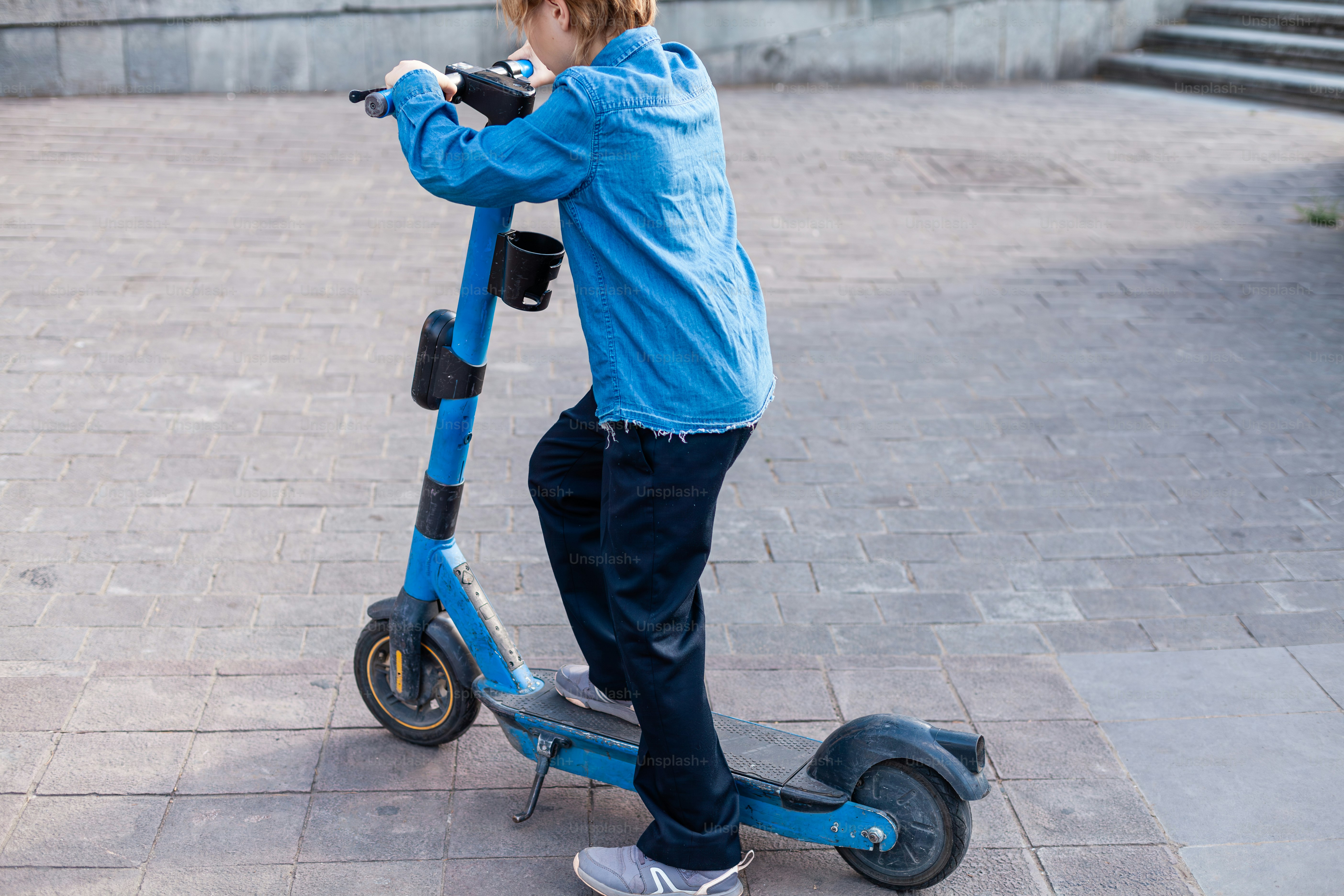 a young boy riding a scooter on a sidewalk