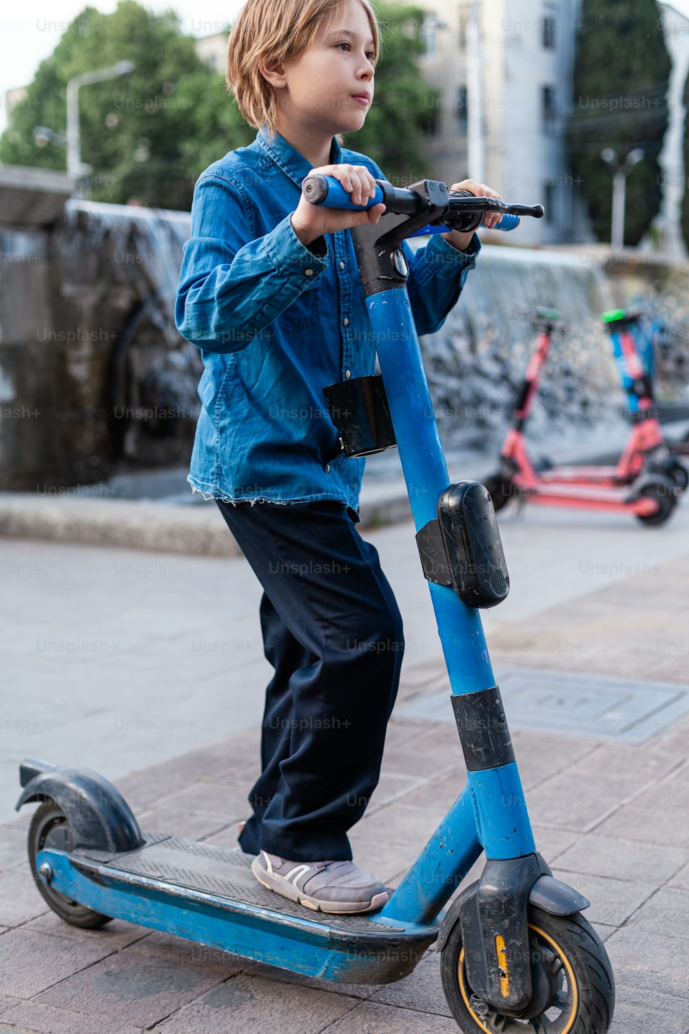 a young boy riding a scooter on a sidewalk