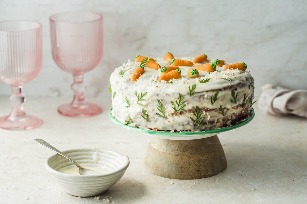 a cake with carrots on top of it next to a bowl of yogur