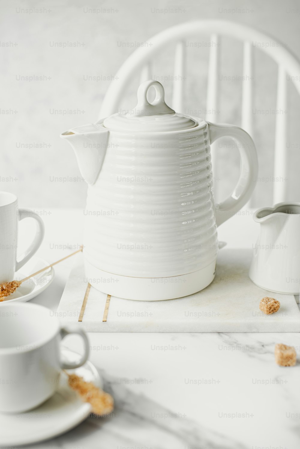 a white tea pot sitting on top of a white table