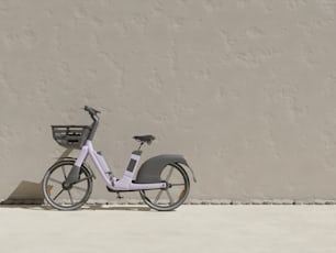 a white bicycle parked next to a gray wall