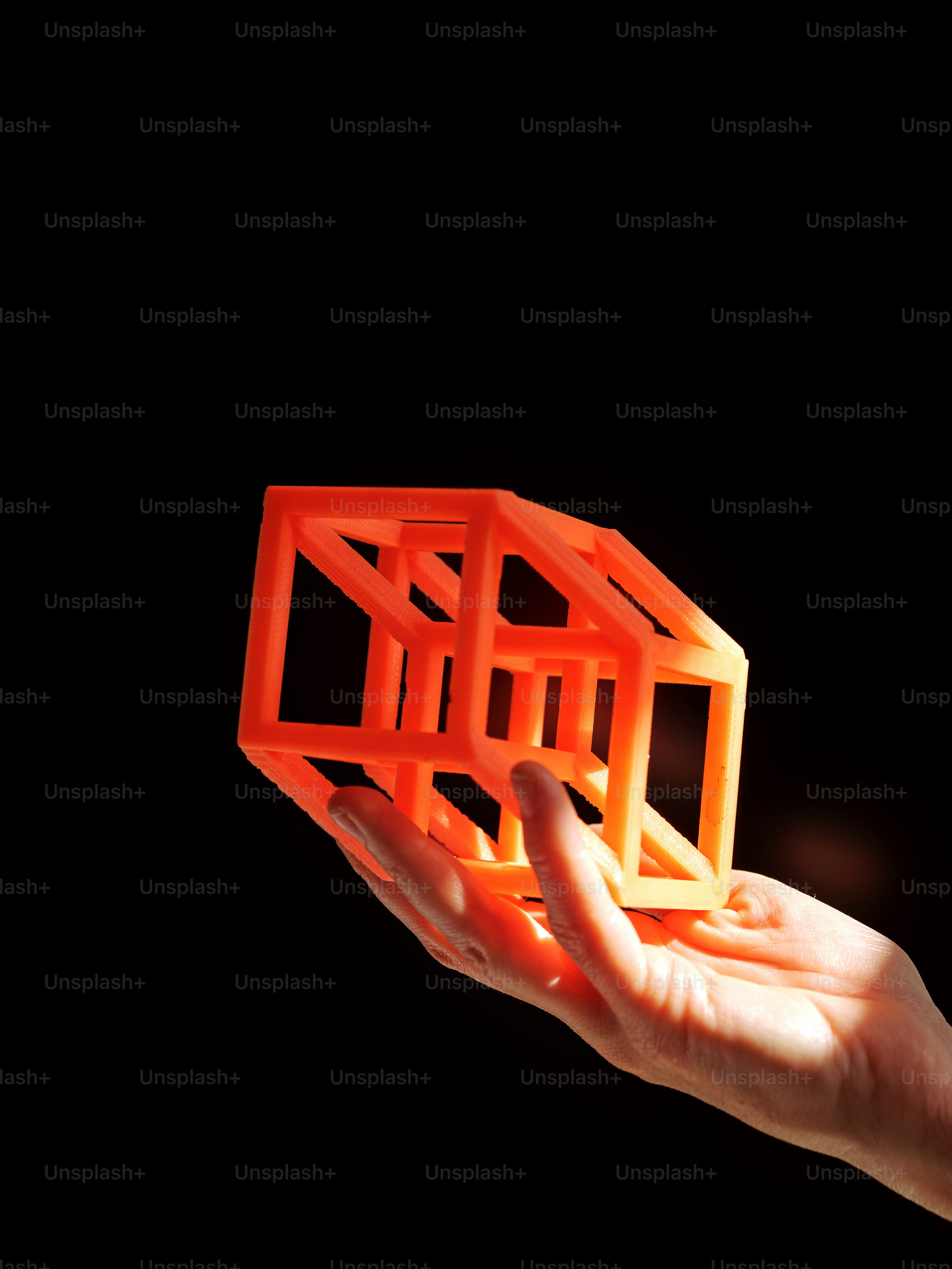 une main tenant un objet orange dans l’obscurité