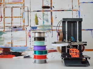 Une pile de fils à côté d’une imprimante 3D