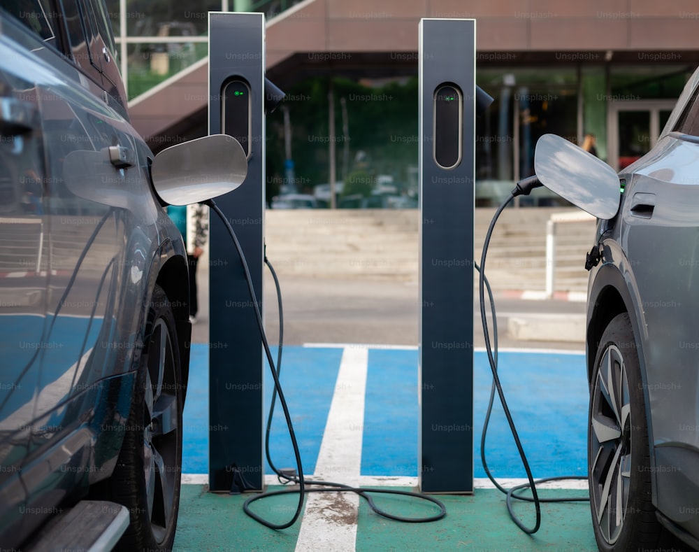 two electric cars plugged in to a charging station