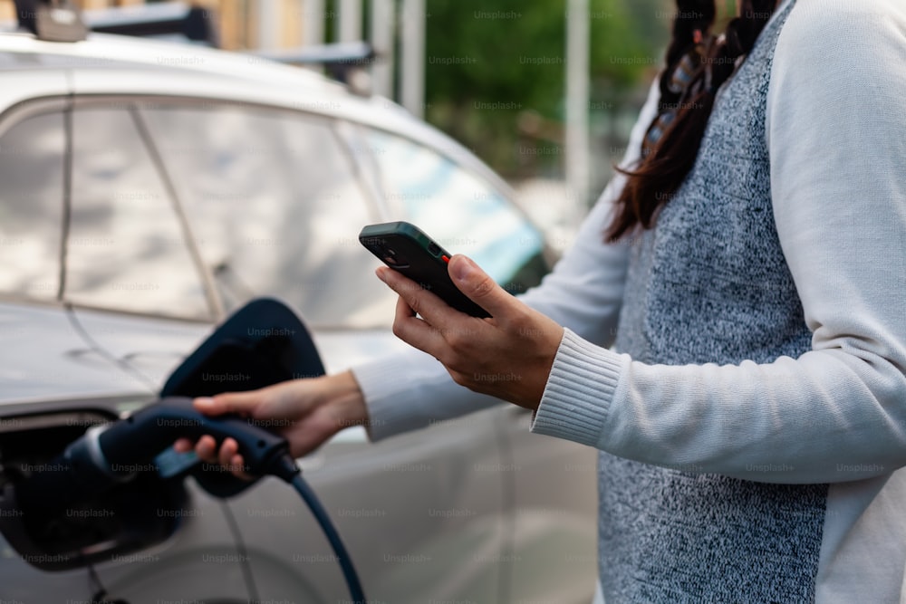 a woman is charging her car with an electric charger