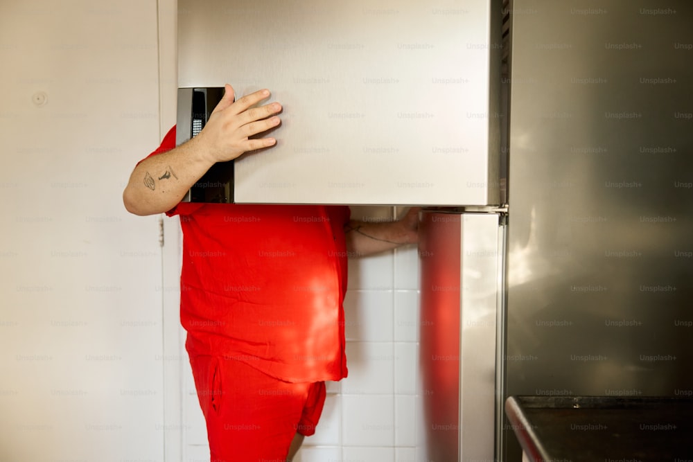 a person hiding behind a refrigerator in a kitchen