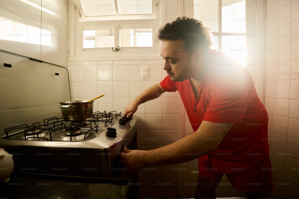 a man in a red shirt is putting a pot on the stove