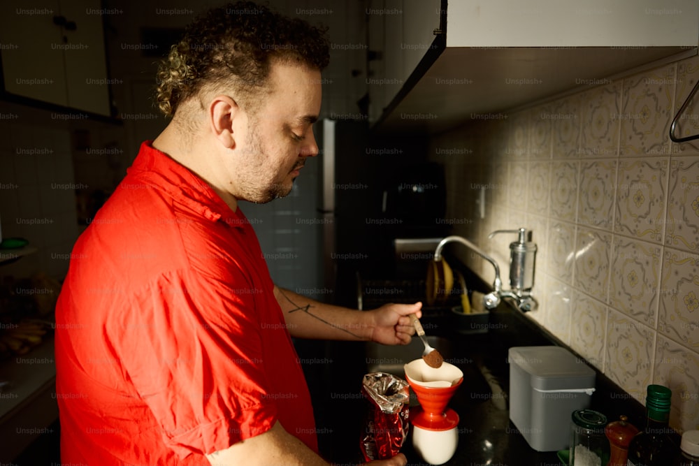 a man in a red shirt preparing food in a kitchen