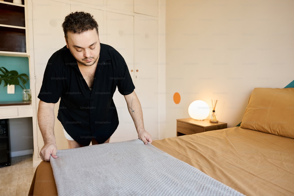 a man standing over a bed in a bedroom