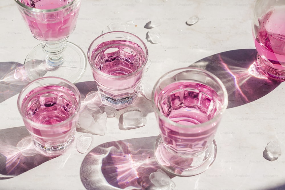 a table topped with glasses filled with pink liquid
