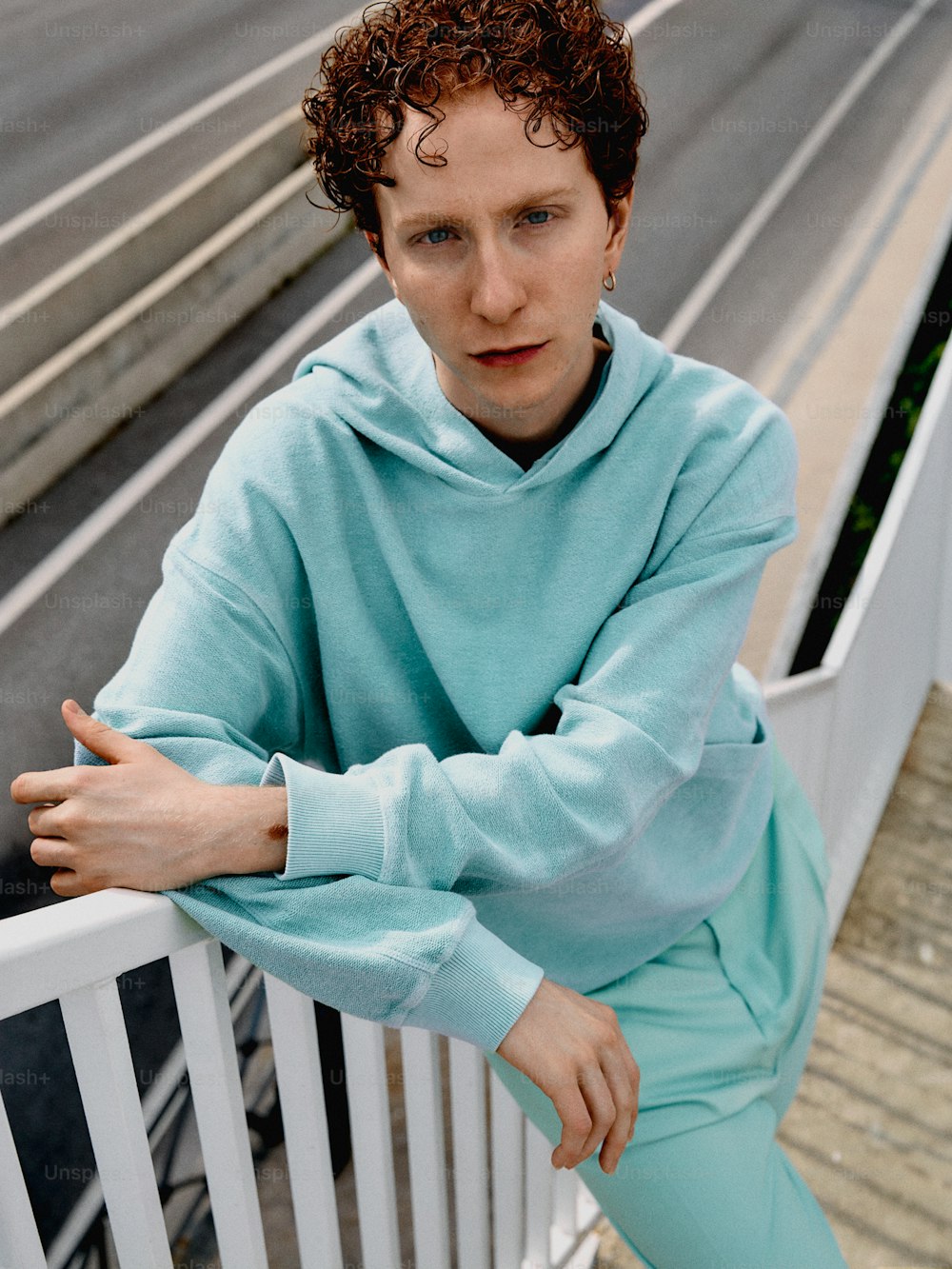 a man in a blue sweatshirt leaning on a white railing