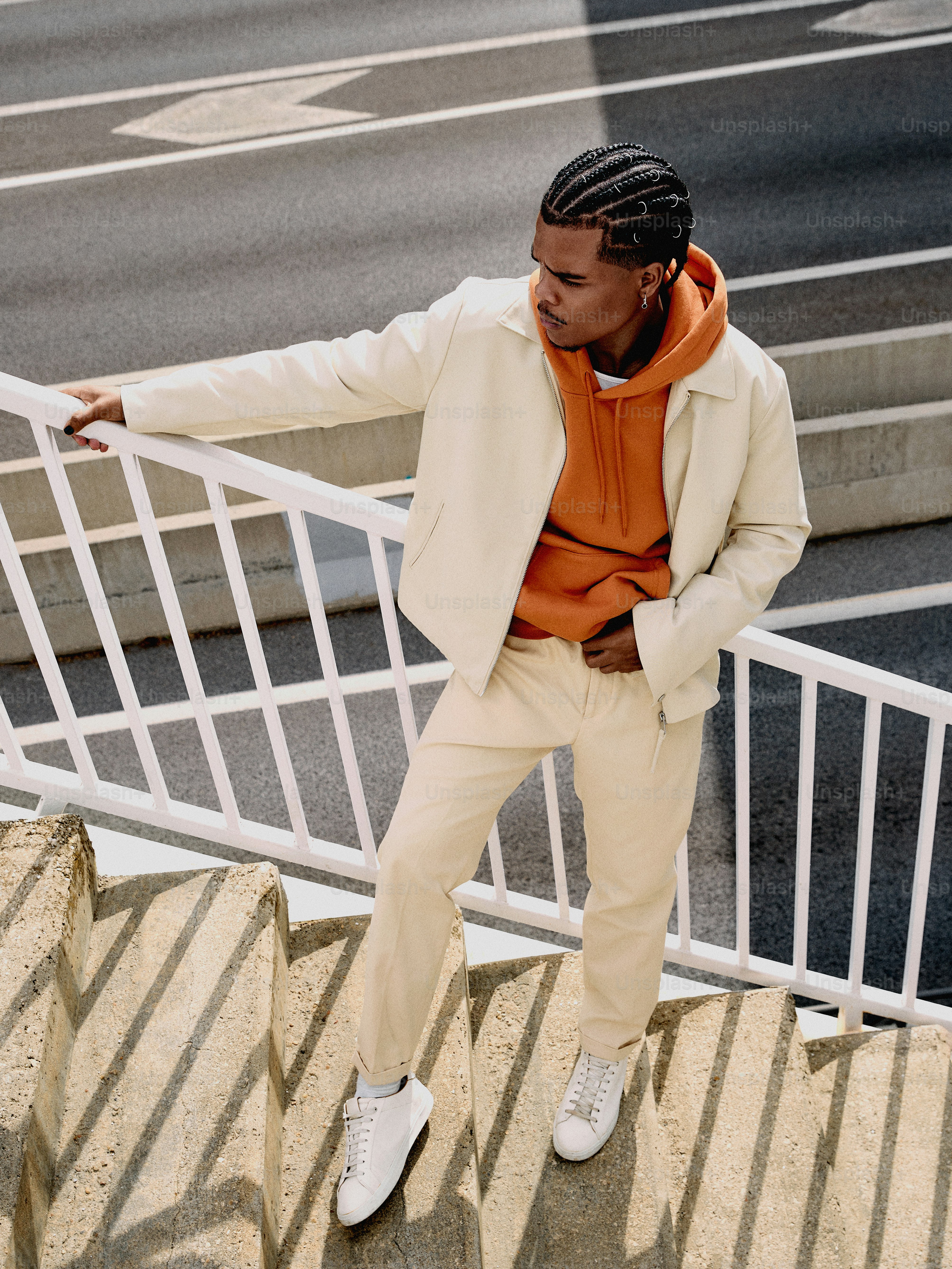 a man in an orange shirt and white suit leaning on a railing
