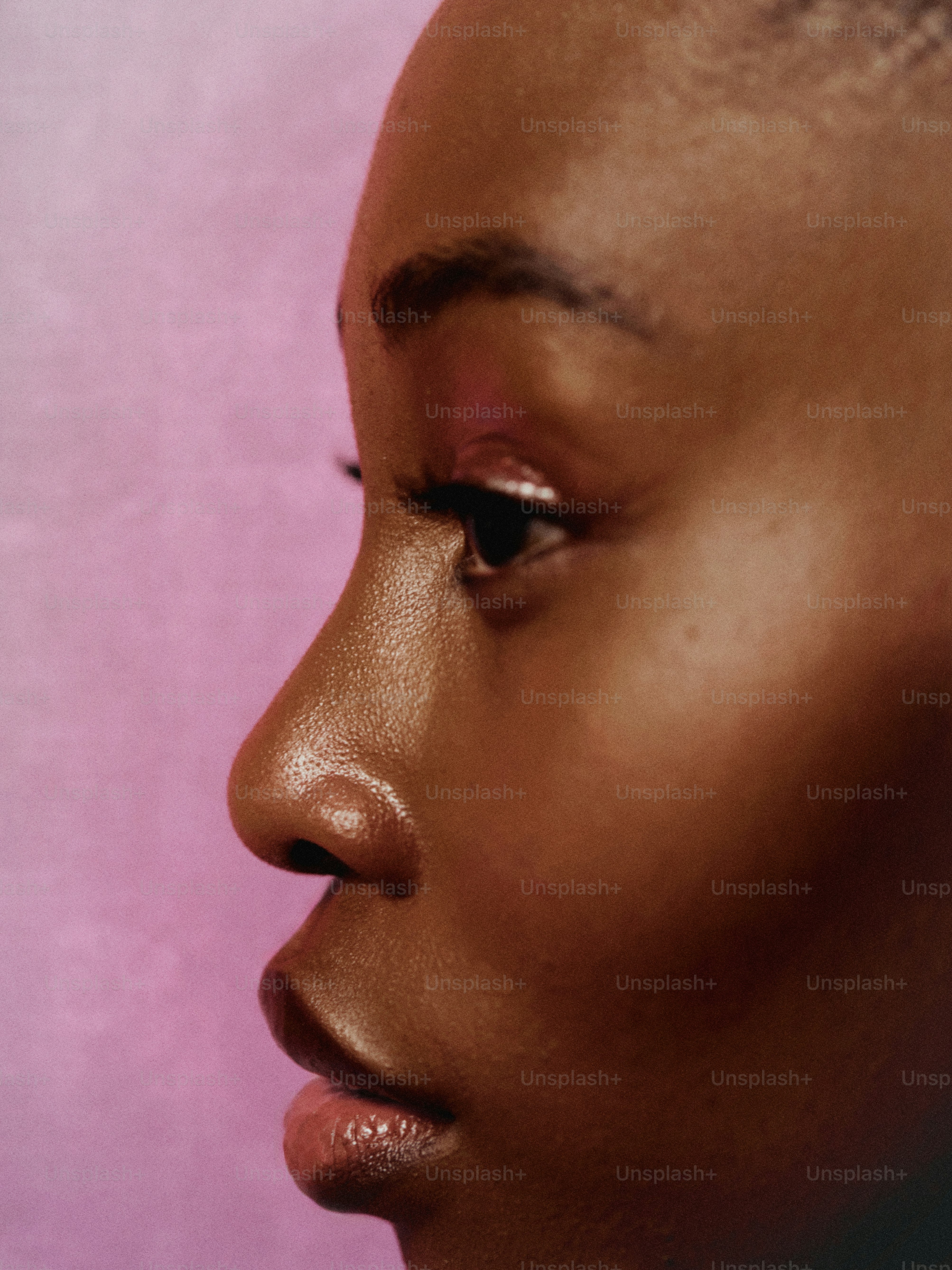 a close up of a woman's face with a pink background