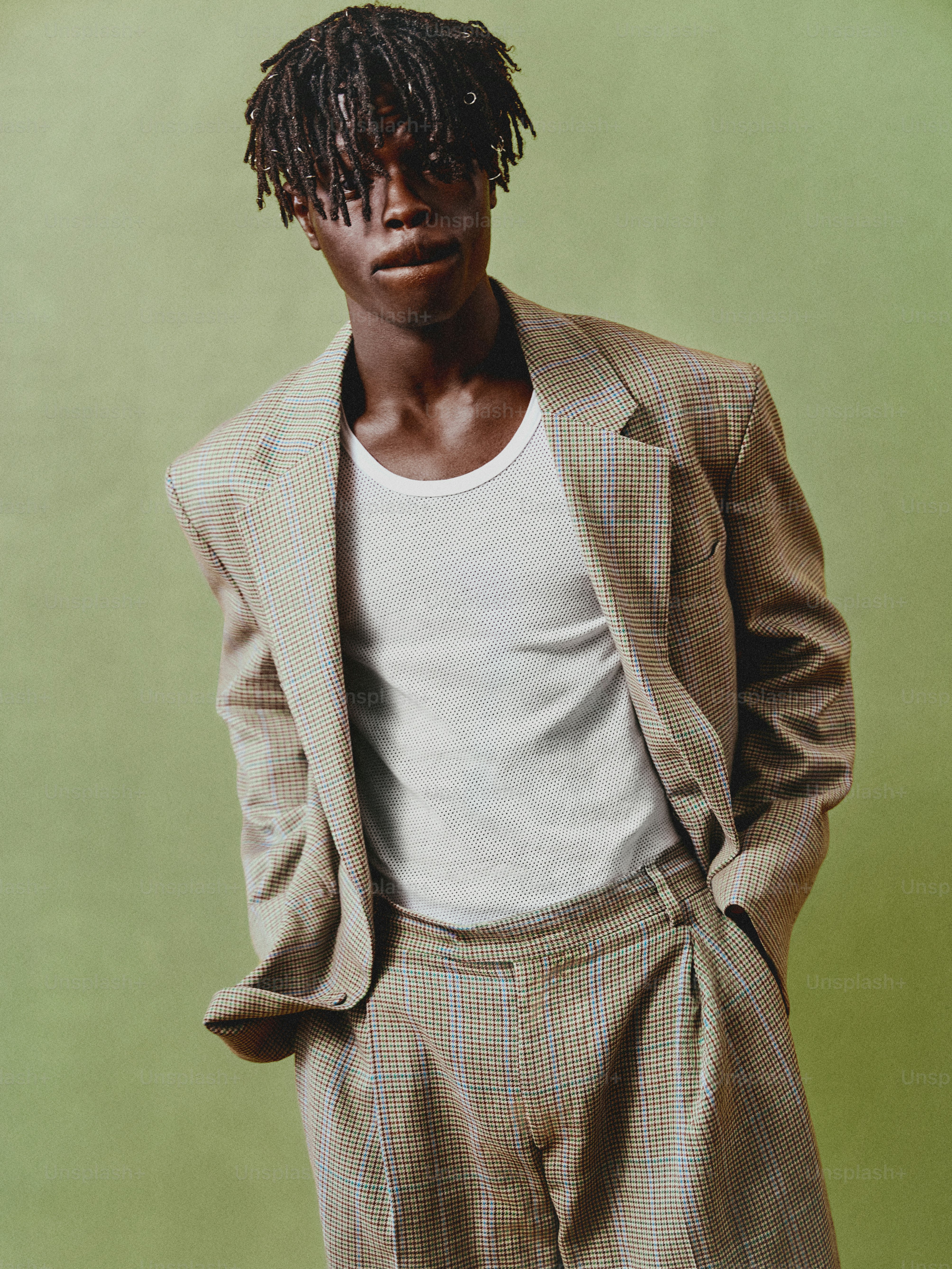 緑の背景の前に立っているドレッドヘアの男