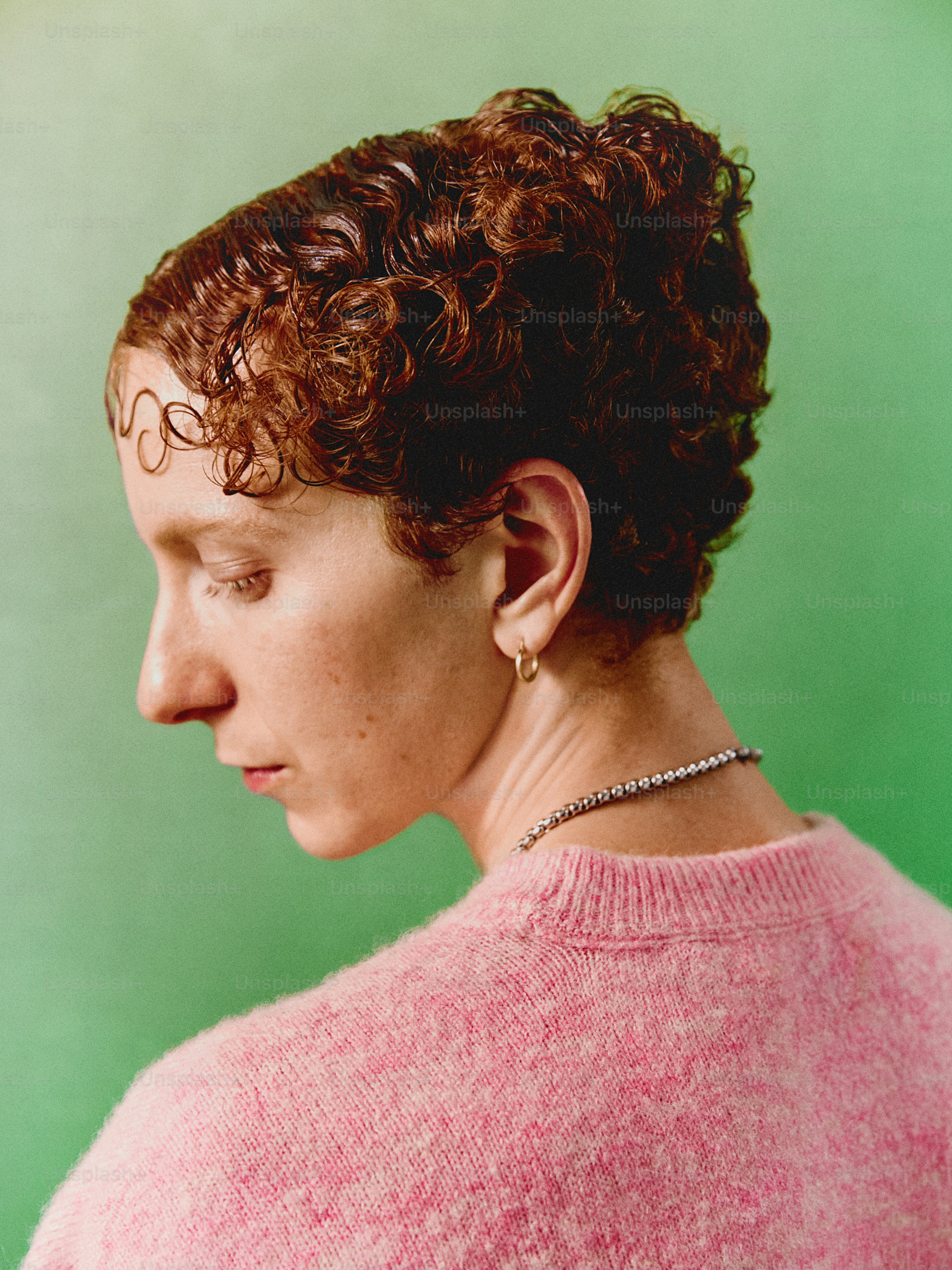 a woman with curly hair wearing a pink sweater