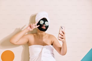 una donna che indossa una maschera nera con in mano un telefono cellulare