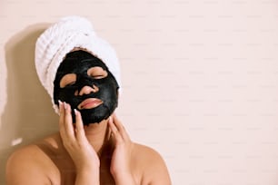 a woman with a towel on her head and a black mask on her face