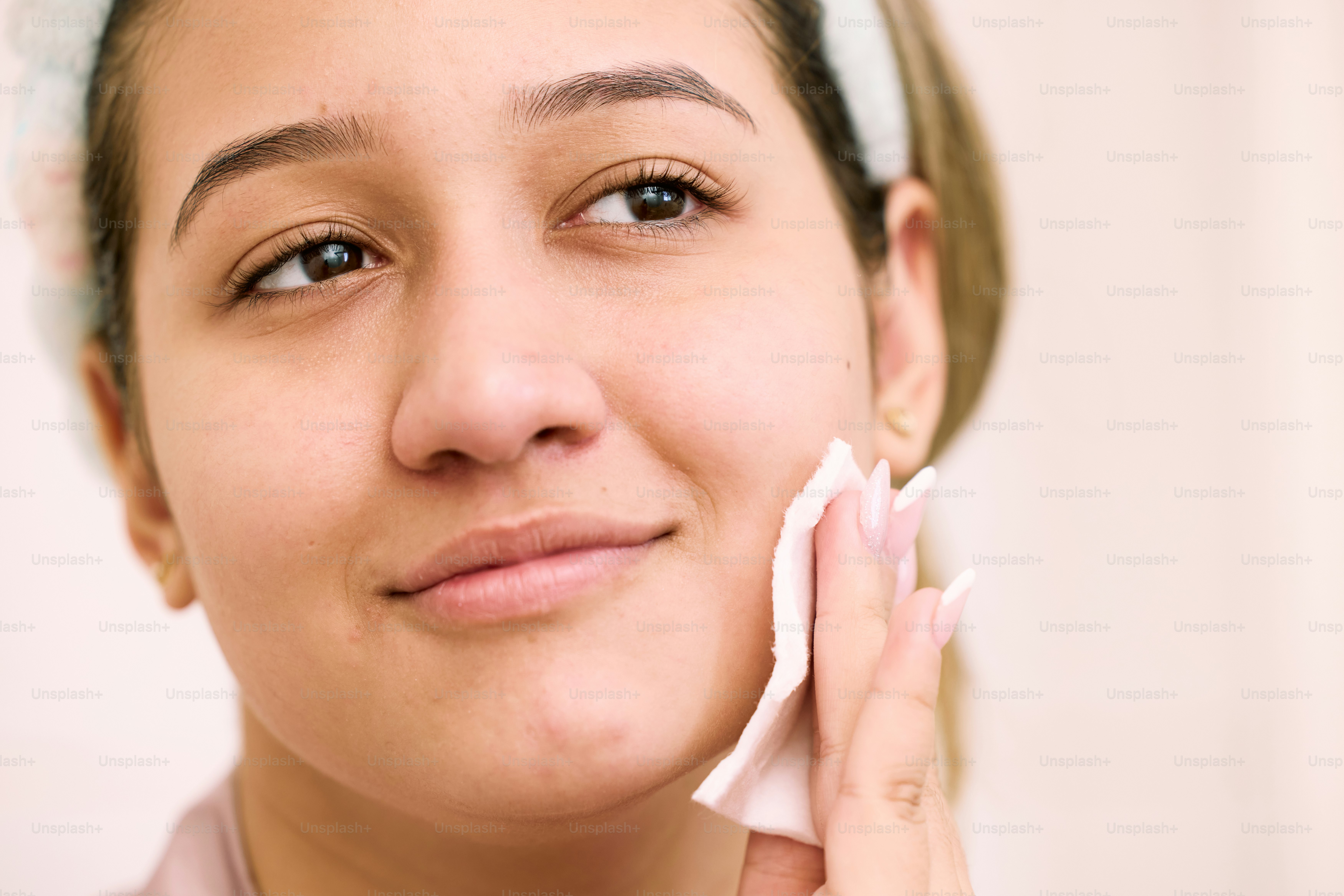 a woman is cleaning her face with a cloth