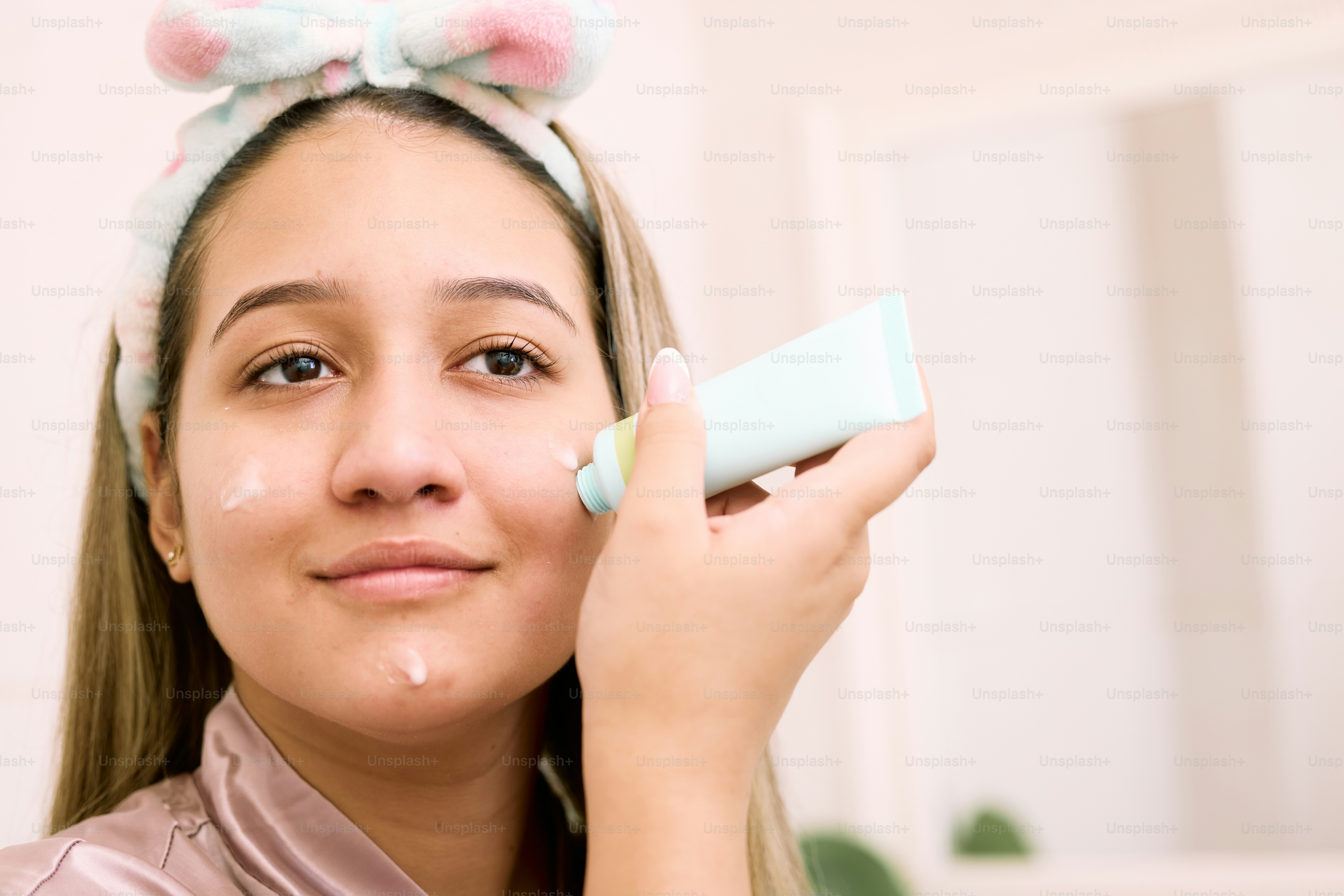 a woman with a bunny ears on her head is applying a cream on her face