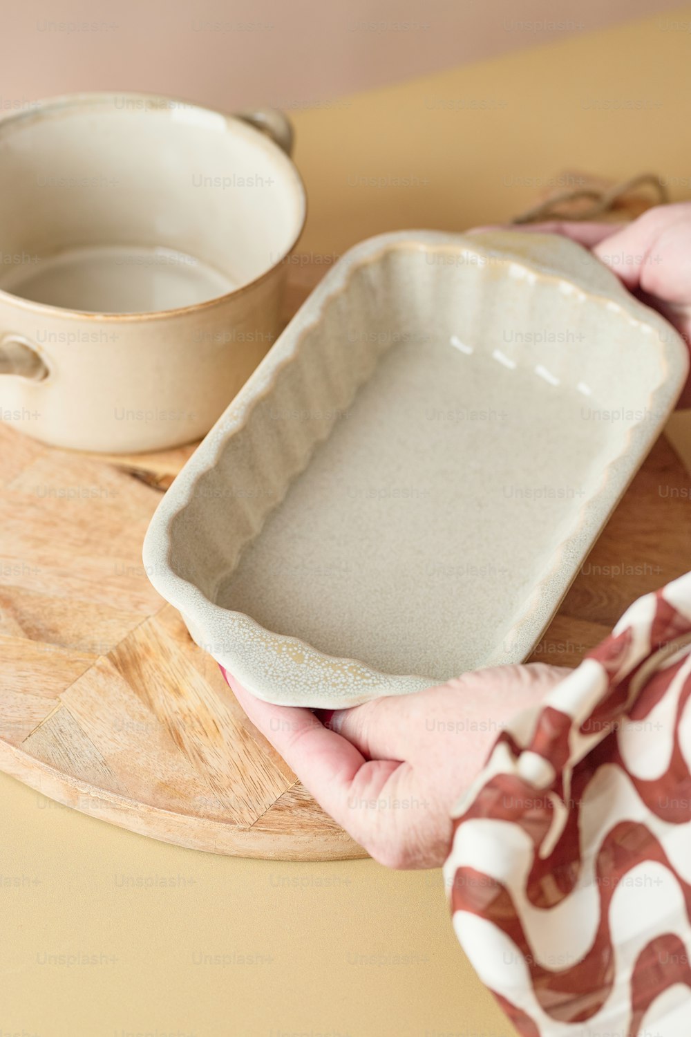 a person holding a baking dish on a wooden tray