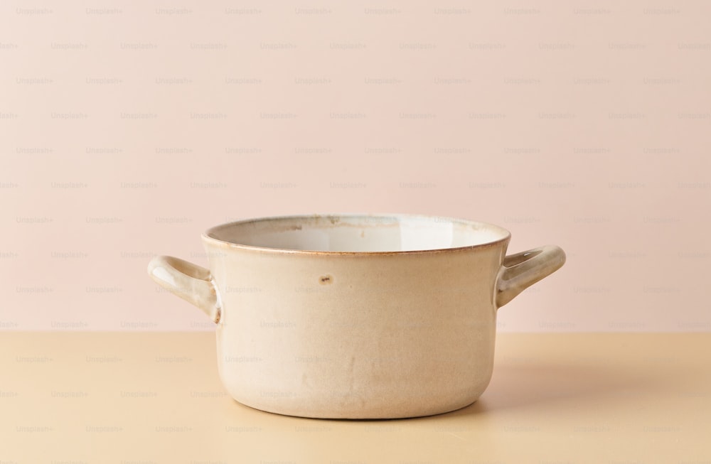 a white bowl with a handle on a table