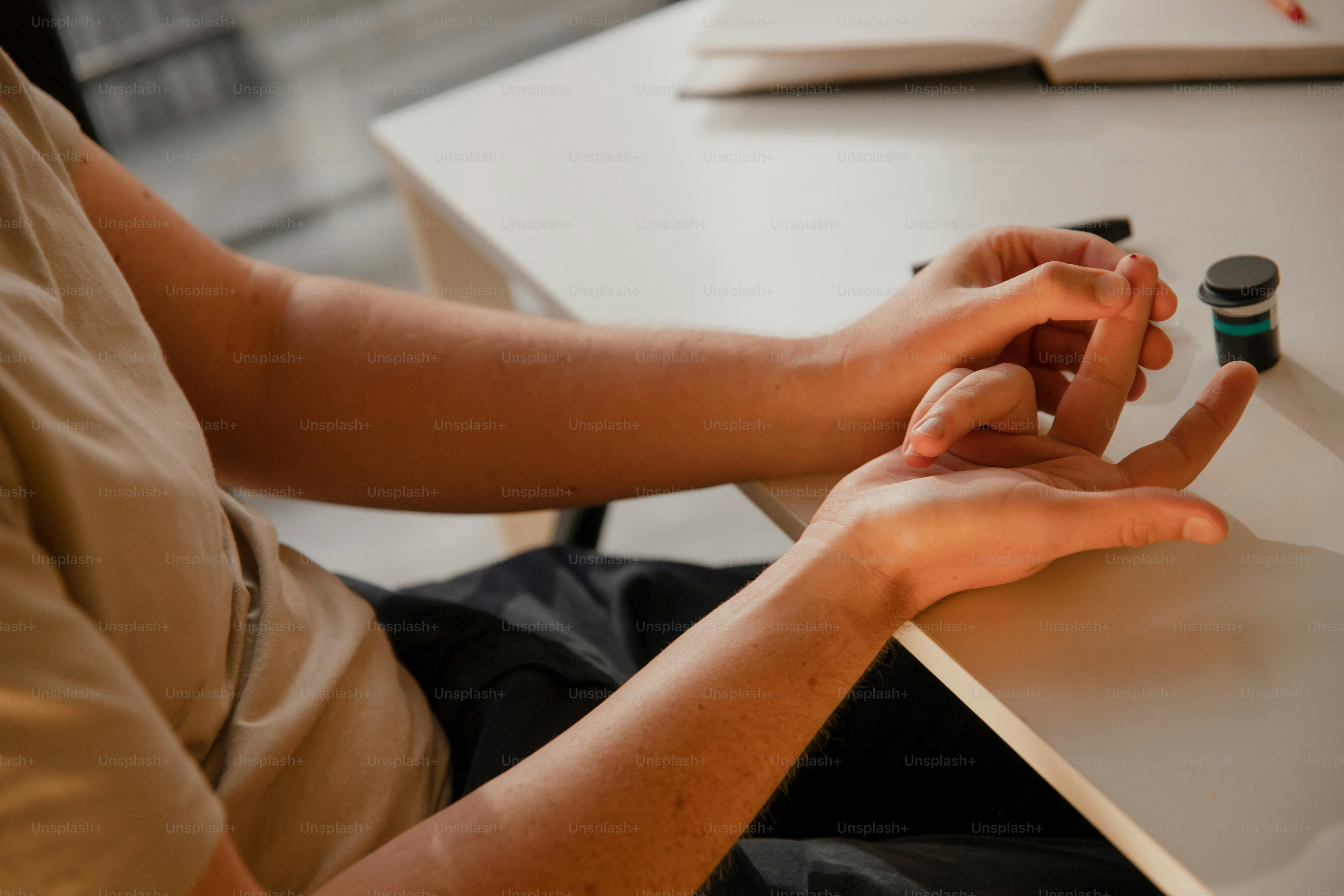eine Person, die mit einem Stift in der Hand an einem Tisch sitzt