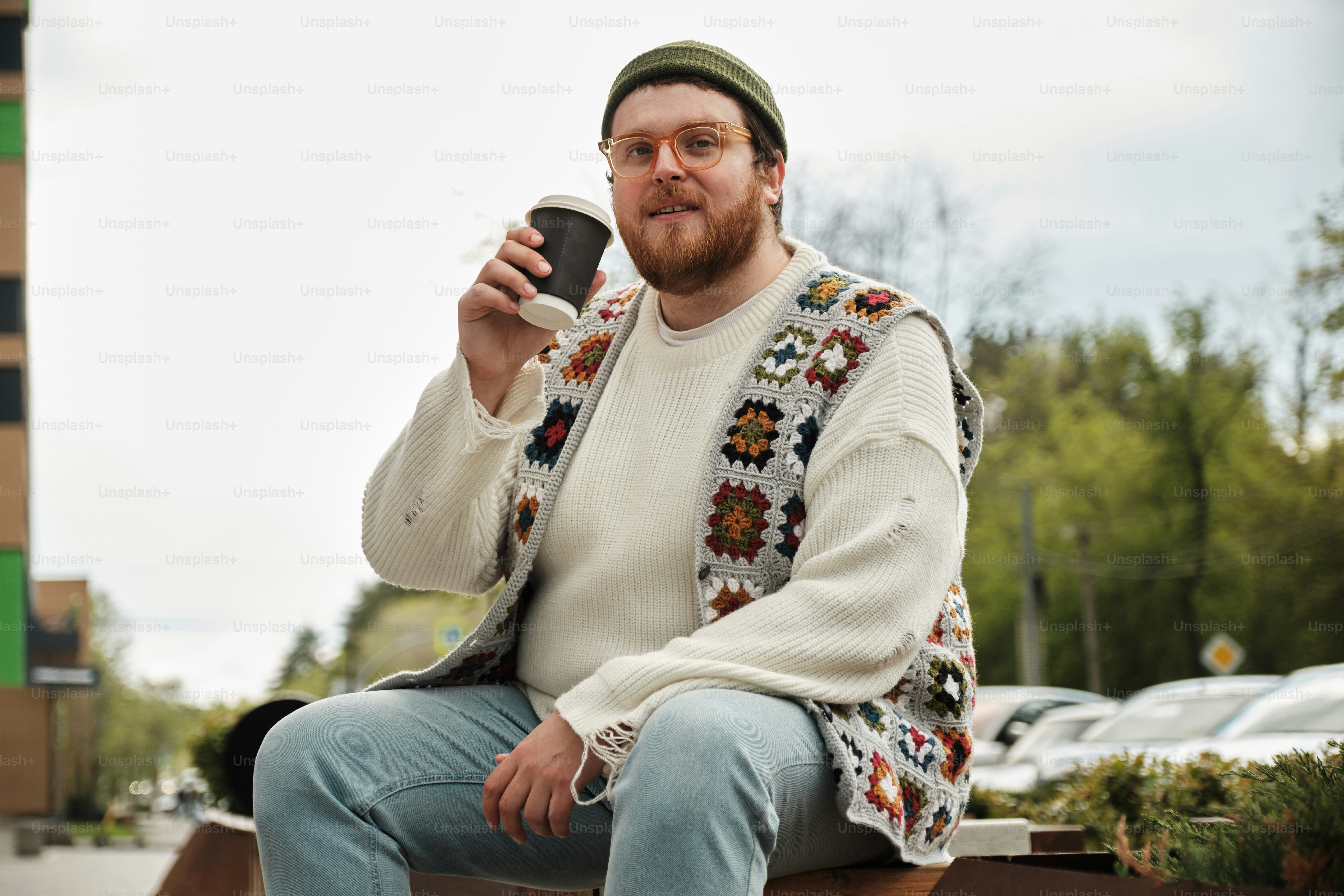 a man sitting on a bench holding a cup of coffee