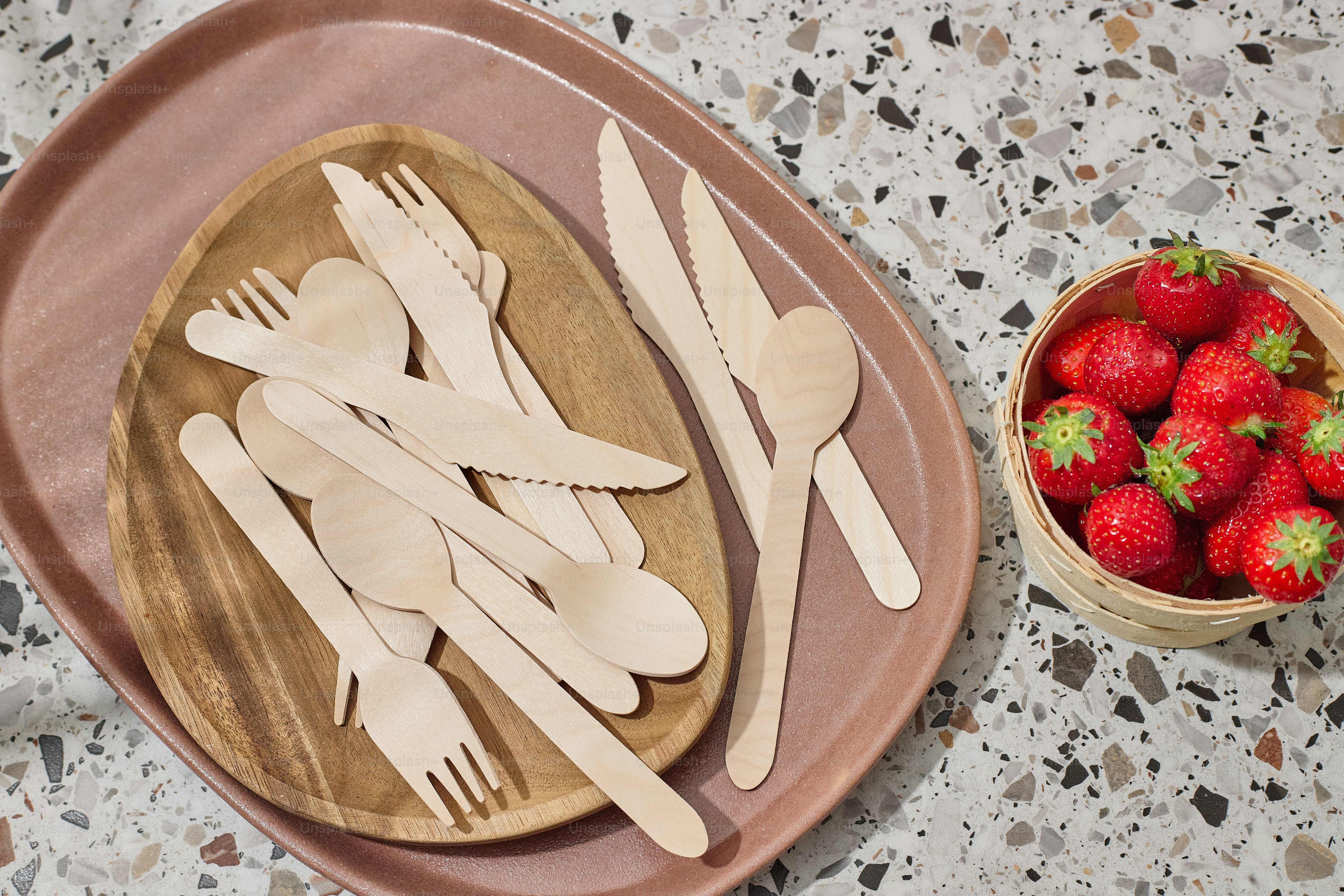 un cuenco de fresas y utensilios de madera sobre una mesa