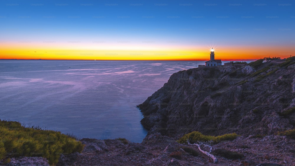 a lighthouse on a cliff overlooking the ocean at sunset