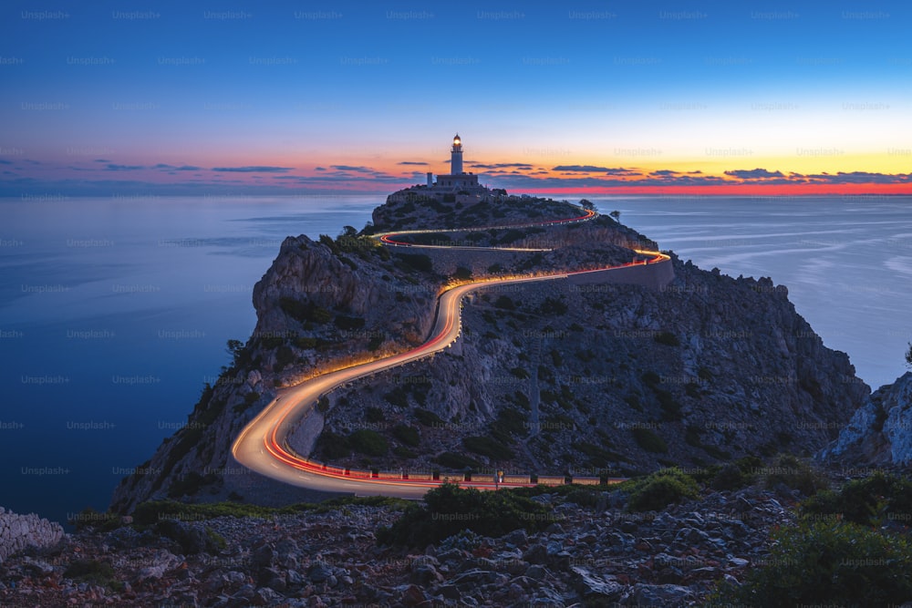 a long exposure shot of a winding road leading to a lighthouse