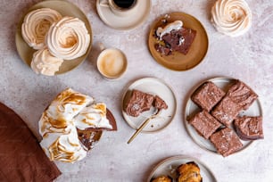 a table topped with plates of desserts next to a cup of coffee