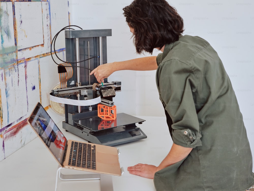 a man working on a laptop computer next to a 3d printer